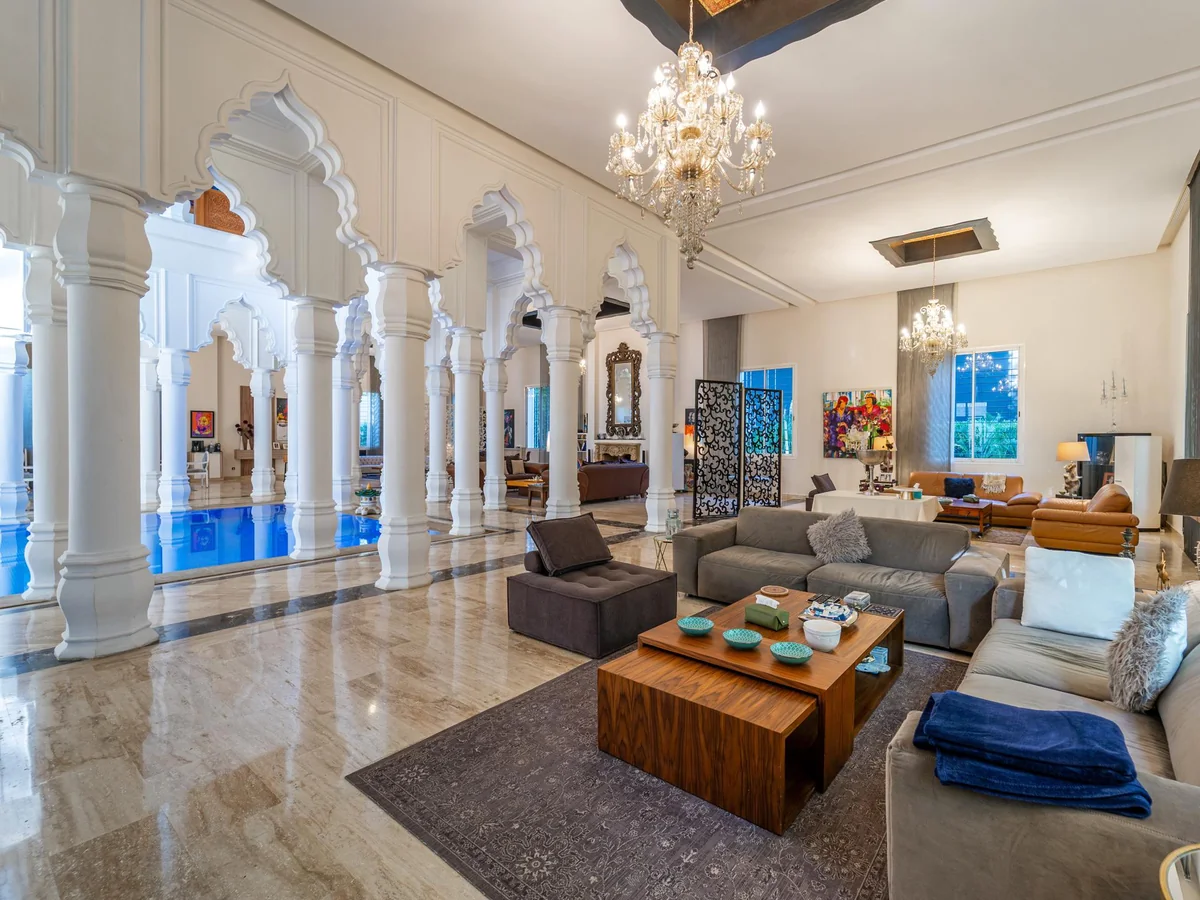 Spacious villa interior with ornate arches, chandeliers and an indoor pool