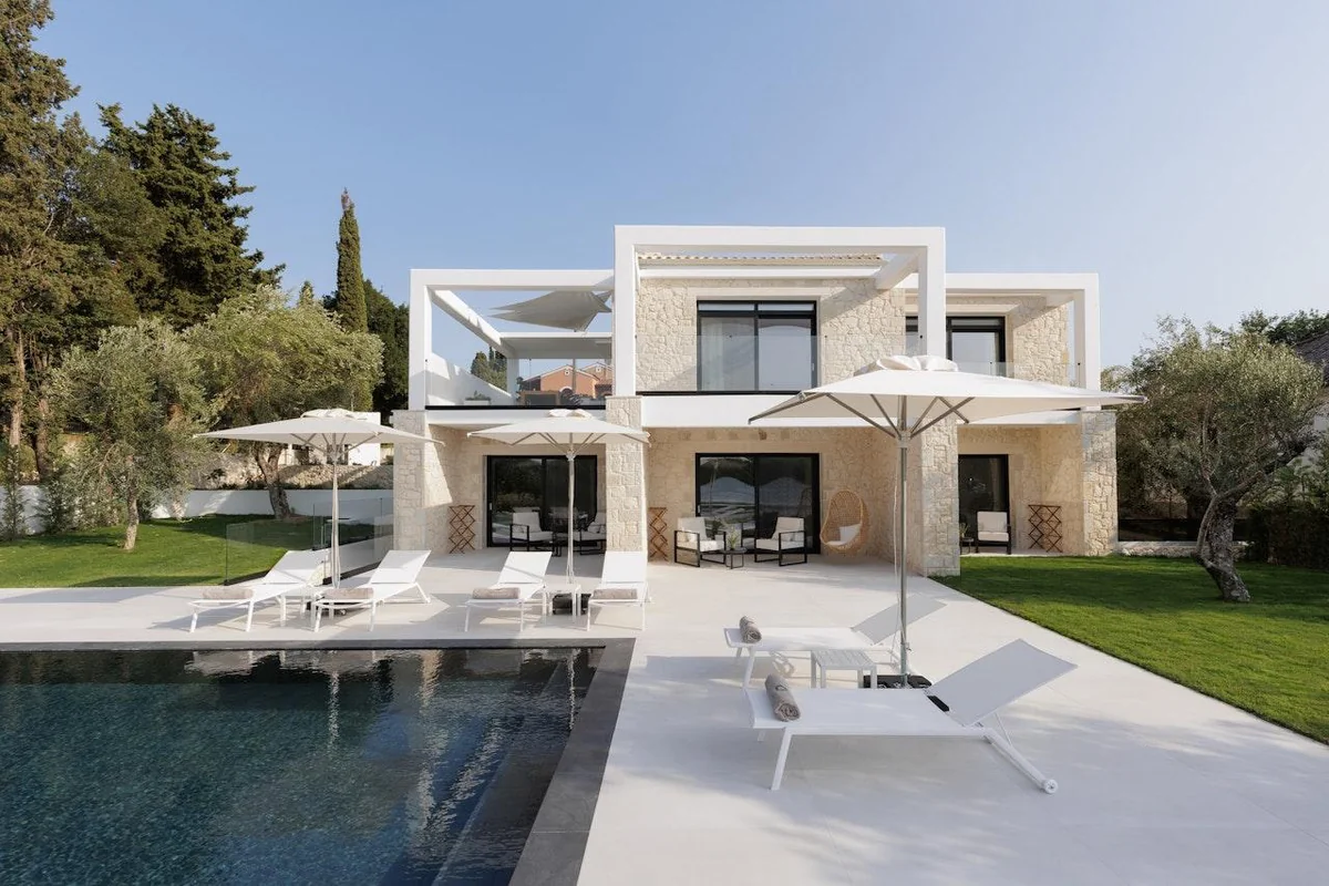 Contemporary stone villa with a swimming pool, white loungers and garden