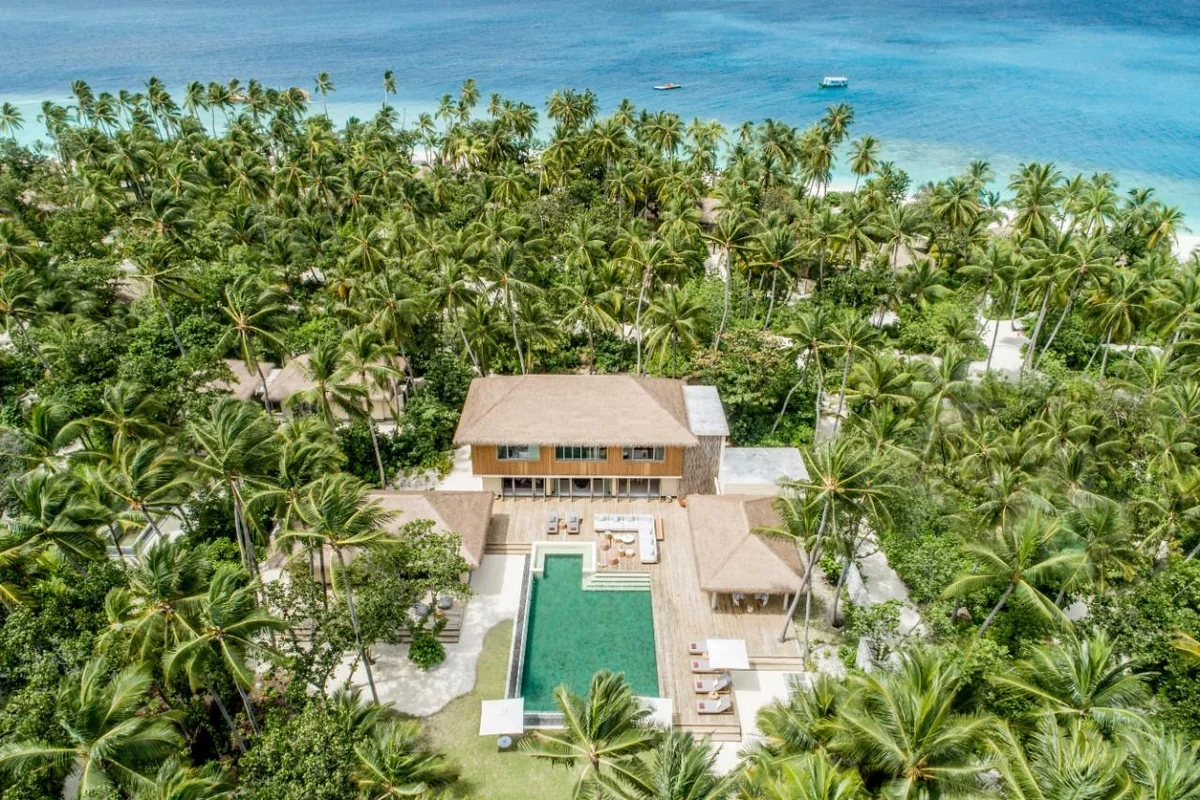 Aerial view of a tropical coastal villa with a private pool surrounded by palm trees