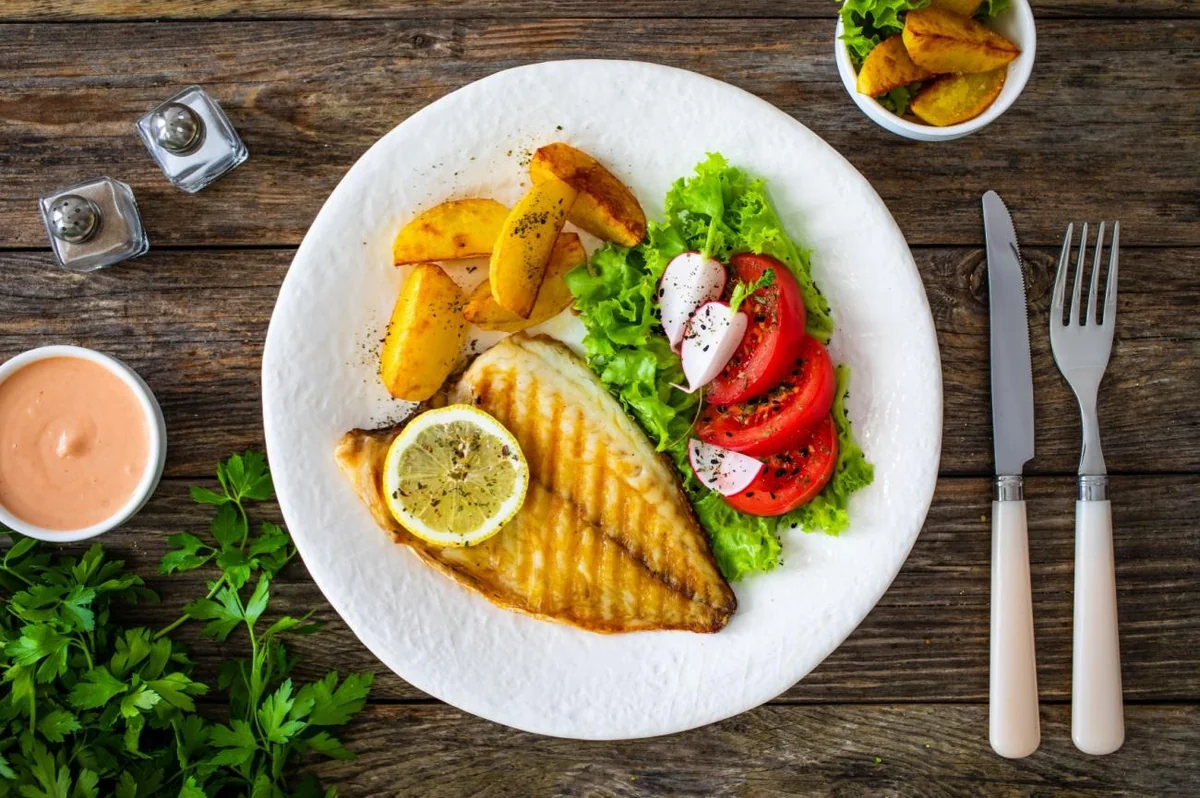 Grilled fillet with lemon, potato wedges and fresh salad