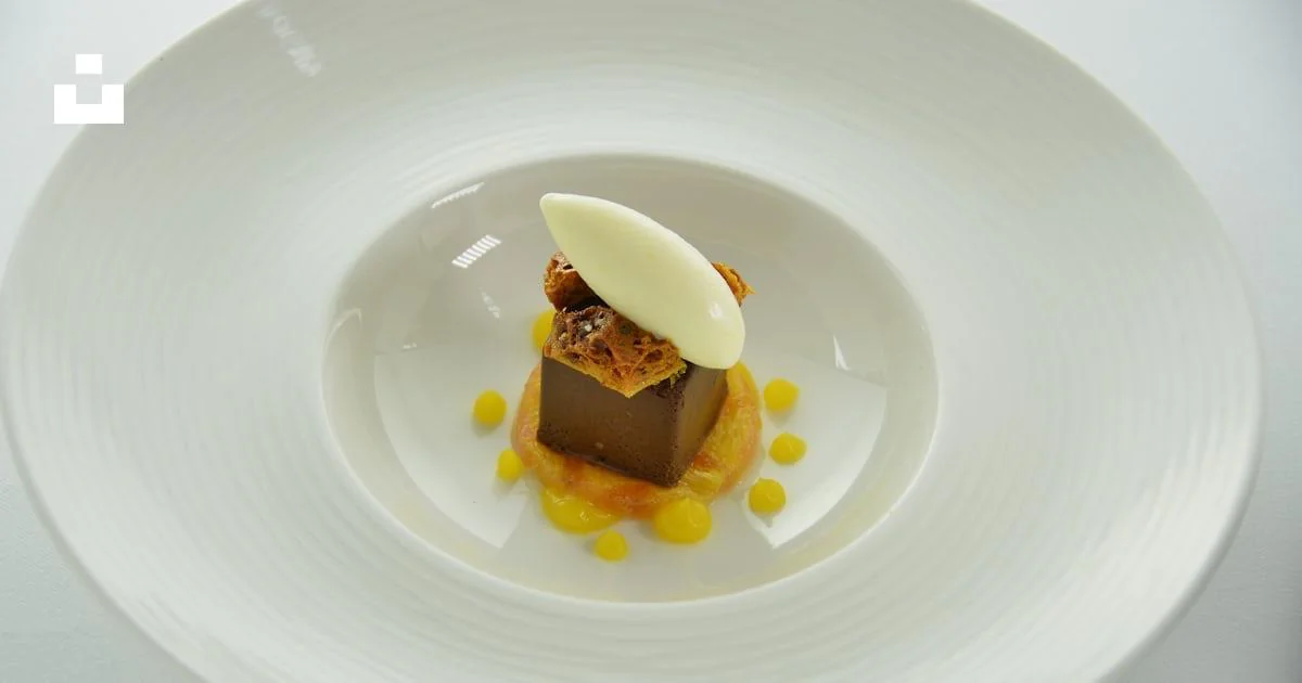 Chocolate dessert topped with a cream quenelle on a white plate