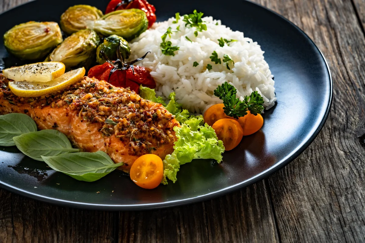 Salmon served with rice, lemon and roasted vegetables
