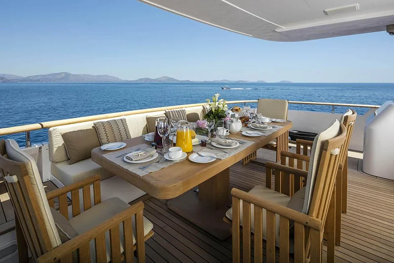 Shaded yacht deck with a dining table set overlooking the sea