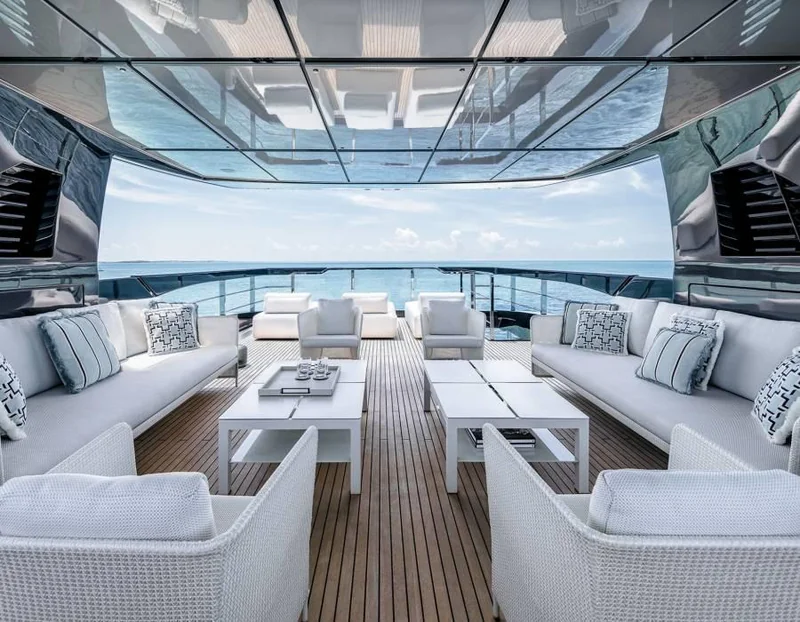 Covered yacht lounge with white seating, teak decking and an open sea view