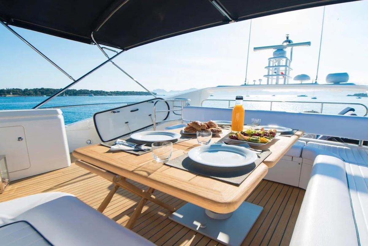 Breakfast table with pastries, fruit and juice on a shaded yacht deck