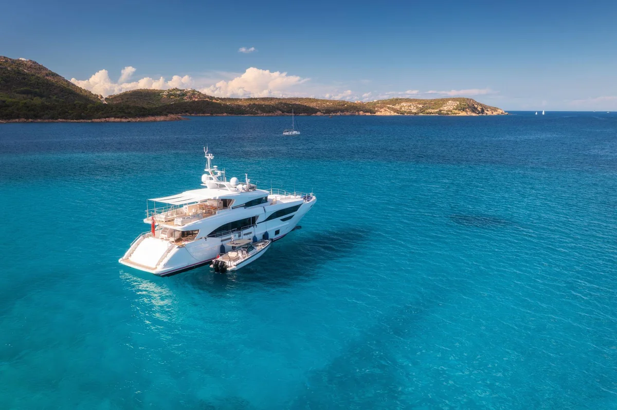 Luxury motor yacht and tender anchored in a turquoise bay