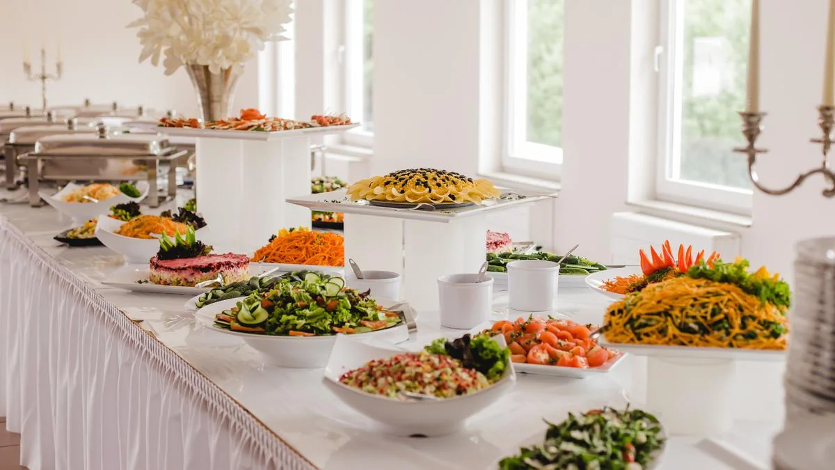 Fresh salads and vegetable dishes arranged on a white buffet table