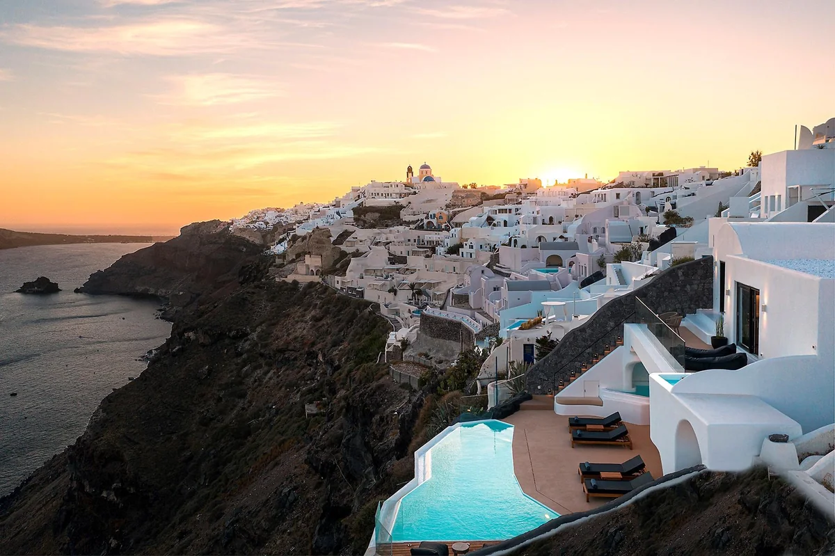 White cliffside buildings and infinity pools overlooking the sea at sunset