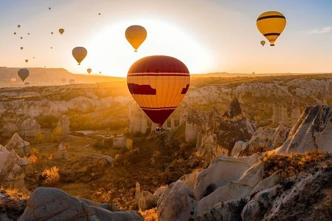 Hot air balloons floating above rocky valleys at sunrise