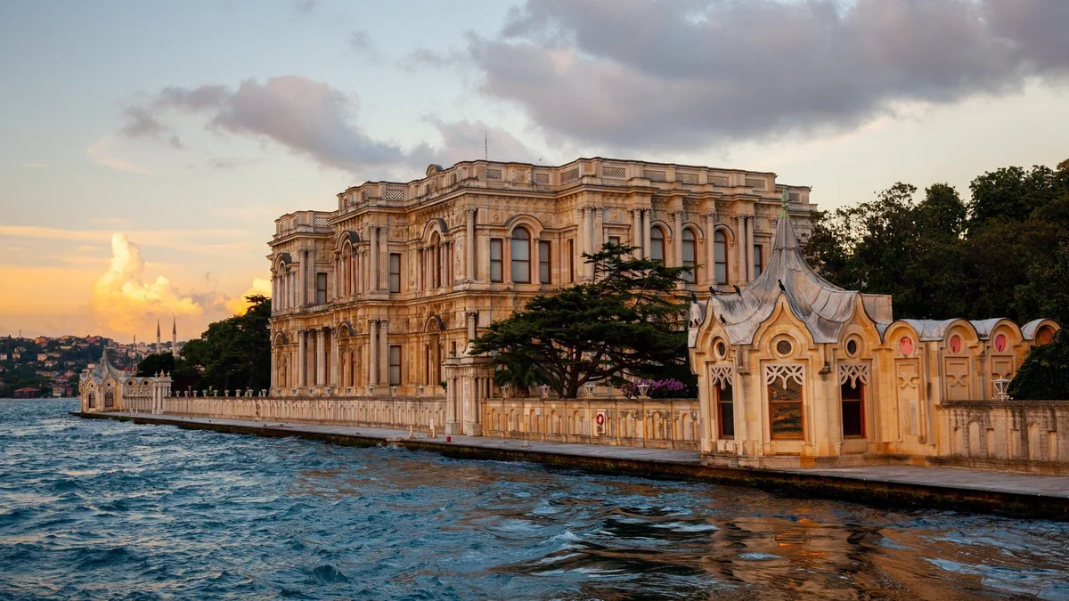Ornate waterfront palace and garden walls beside the water at sunset